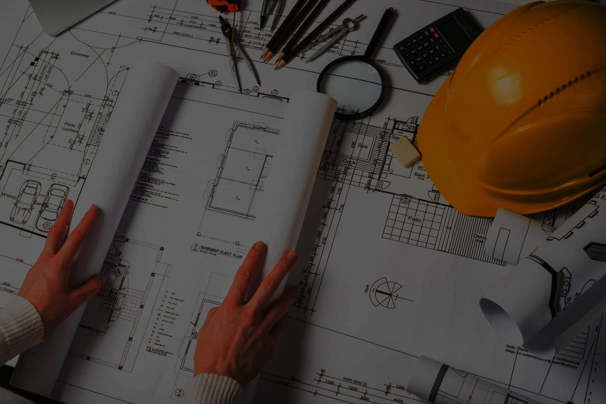 Engineer reviewing construction blueprints with hardhat and tools on desk